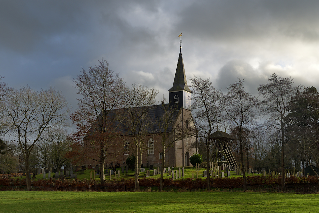 De kerk van Wijnjeterp tegen een dreigende wolkenlucht